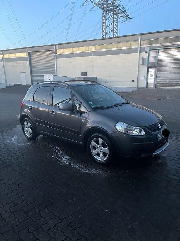 Grau Gebraucht 2010 Suzuki SX4 Comfort Limousine | 5.899 € (Fairer Preis) - Bild 1/4