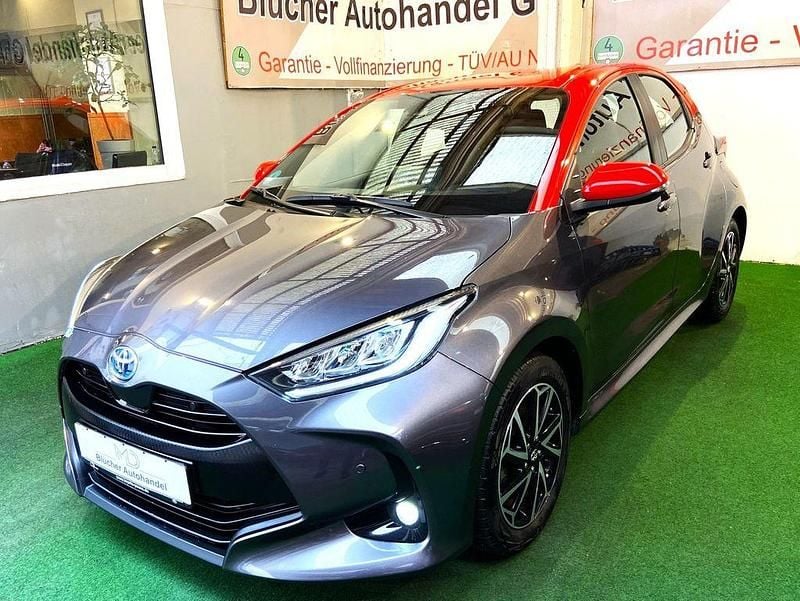 Grey metallic/ coral ro (metallic) Gebraucht 2021 Toyota Yaris Hybrid Limousine | 18.950 € (Fairer Preis) - Bild 1/4