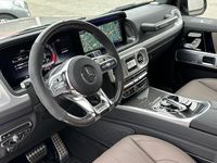 tweedehands Mercedes G63 AMG AMG Grijs Kenteken 2024 | Manufaktur Leder Exclusief | Carbon Interieur + Stuur | Massage | Rij-Assistentie | Trekhaak | Burmester | Zitklima | Schuifdak | 22" Kruisspaak Zwart