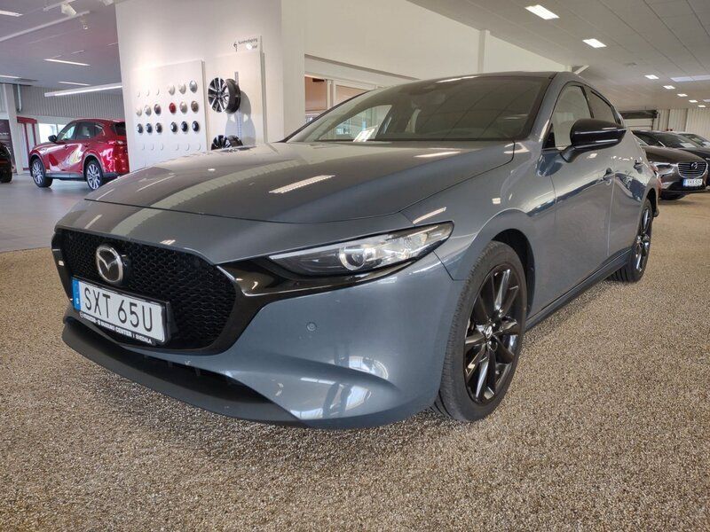 Grå (polymetal grey) Begagnad 2022 Mazda 3 Homura-Line Halvkombi | 249 900 kr (Marknadspris) - Bild 1/4